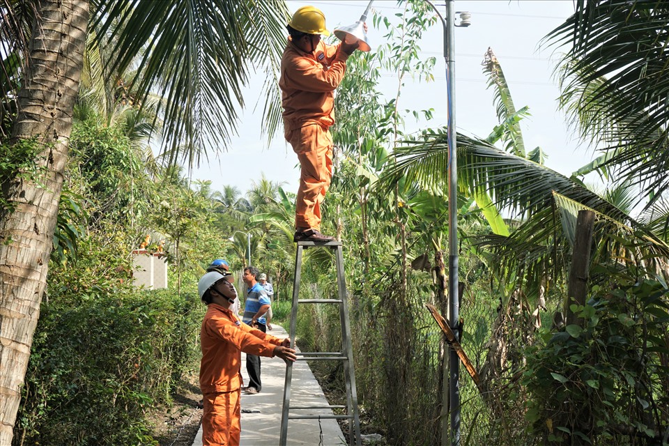 Công nhân Điện lực Càng Long lắp điện “Thắp sáng đường quê“. Ảnh EVNSPC cung cấp.