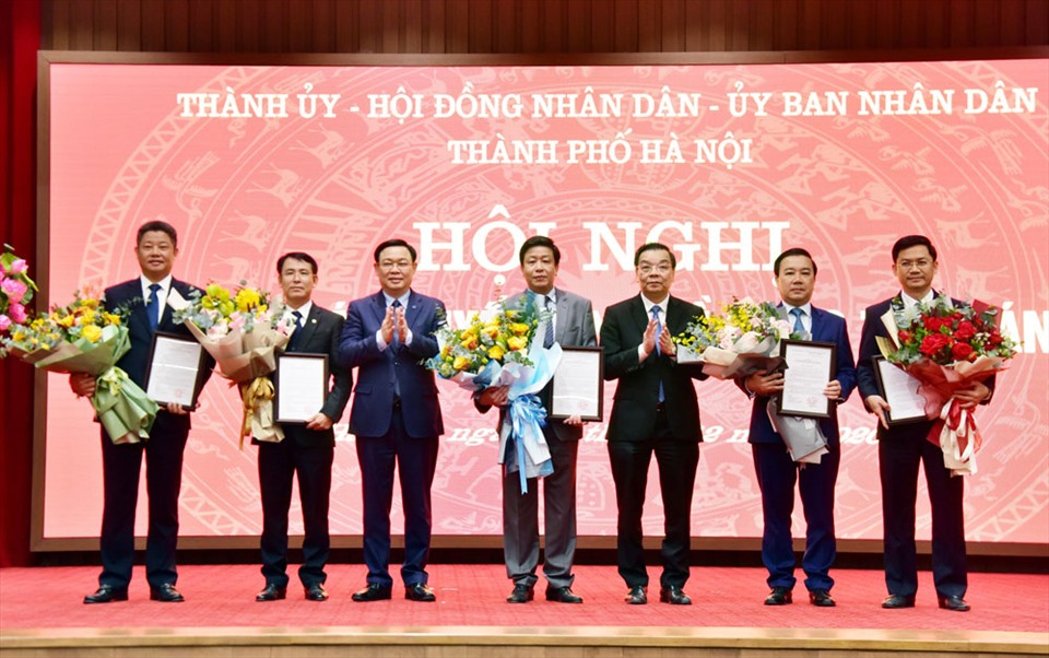 Bí thư Thành ủy Hà Nội Vương Đình Huệ (thứ ba, bên trái) và Chủ tịch UBND Thành phố Chu Ngọc Anh (thứ ba, bên phải) trao quyết định và tặng hoa chúc mừng các tân Phó Chủ tịch UBND Thành phố.