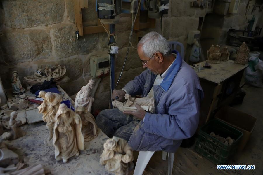 Một nhà điêu khắc người Palestine làm việc trên một tác phẩm điêu khắc bằng gỗ ô liu cho lễ Giáng sinh sắp tới tại một xưởng ở thành phố Bethlehem, Bờ Tây, ngày 22 tháng 12 năm 2020. (Ảnh của Mamoun Wazwaz / Xinhua)