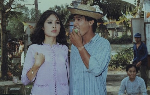 Lý Hùng (phải) với làn da rám nắng trên trường quay phim “Võ sĩ bất đắc dĩ” cùng nghệ sĩ Hồng Vân những năm cuối 1990. Ảnh: Lữ Đắc Long.