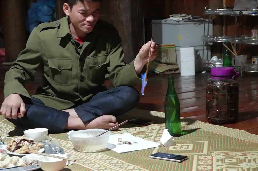 Trong cái lạnh cắt da, Ngân Mạnh Hùng - trưởng bản Mười - đốt rượu ngô đo nồng độ cồn trước khi mời khách ăn cơm tối.