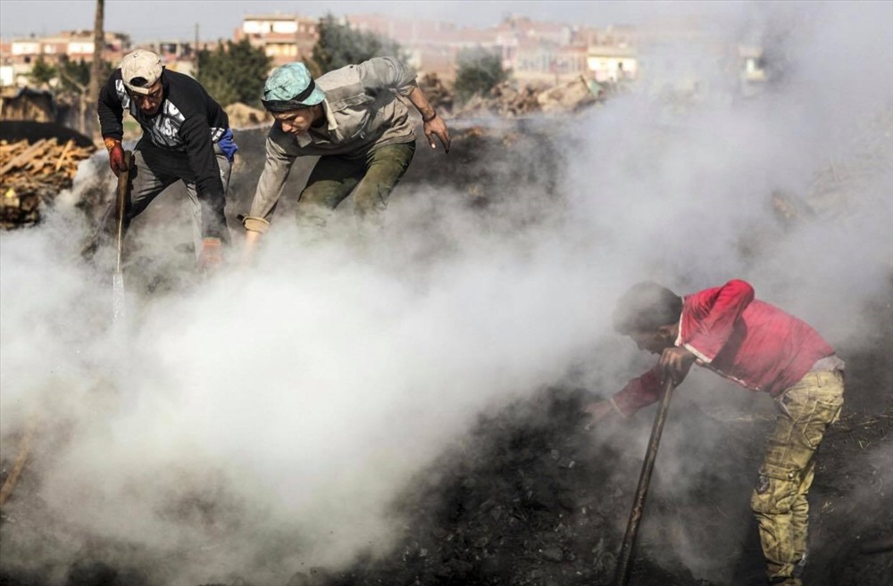Các công nhân làm việc ngay trên than củi đang cháy âm ỉ. Ảnh: AFP