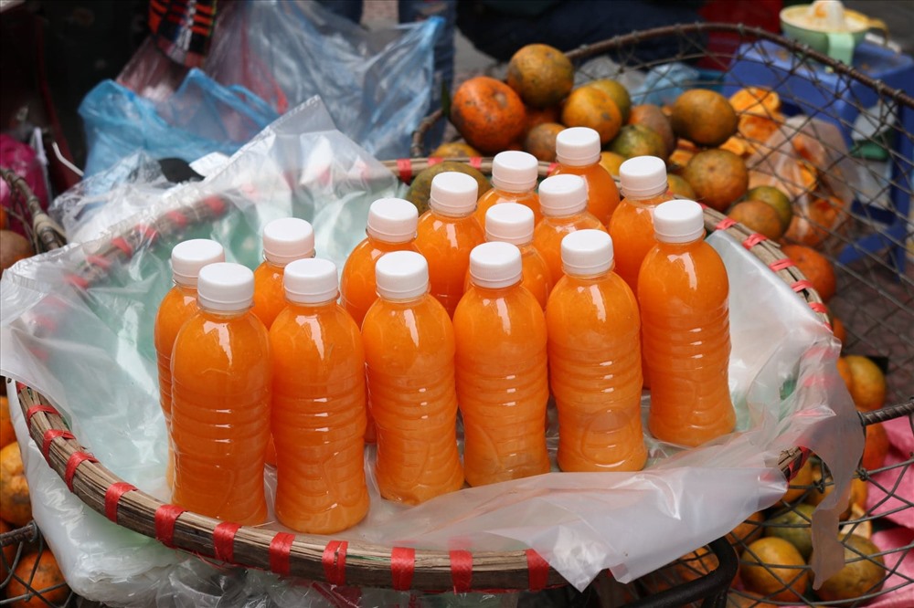 Những chai nước ép cam được tiểu thương bày bán trên các sọt cam nặng trĩu.