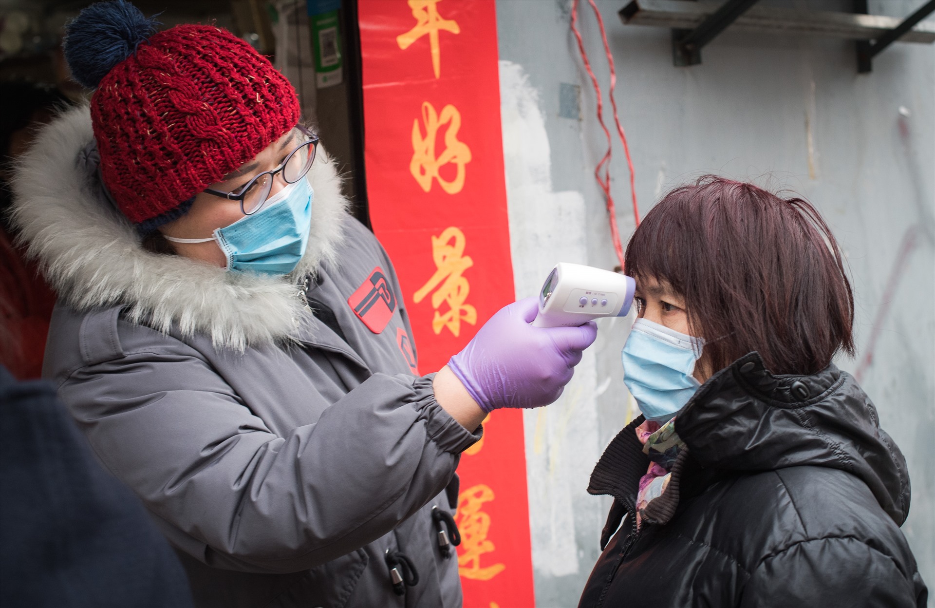 Một nhân viên cộng đồng kiểm tra nhiệt độ cơ thể cho một cư dân tại Vũ Hán. Ảnh: Tân Hoa xã.
