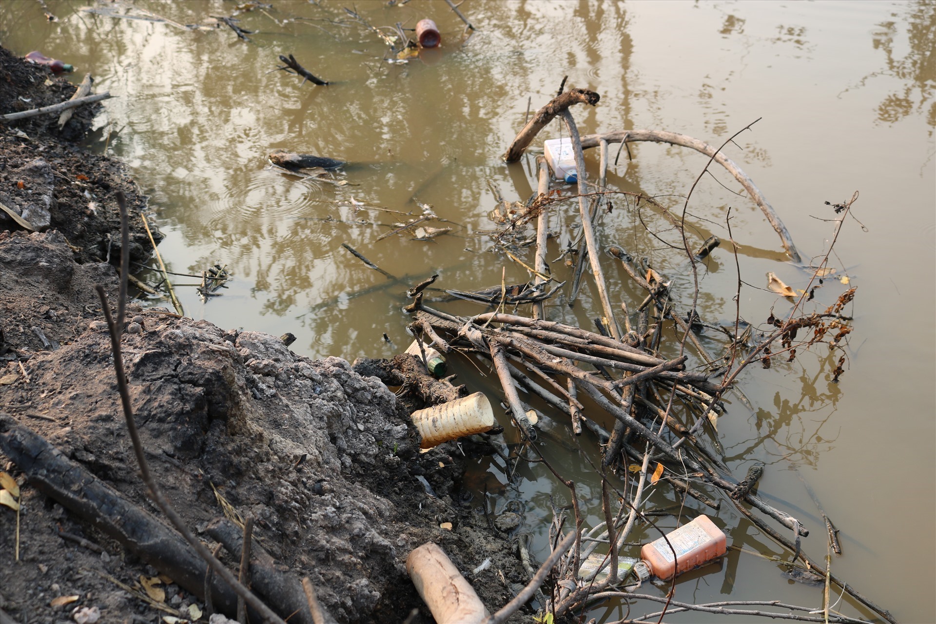 Vỏ chai thuốc bảo vệ thực vật nổi trên mặt nước sau khi thùng rác bị đẩy xuống kênh. Ảnh: LN