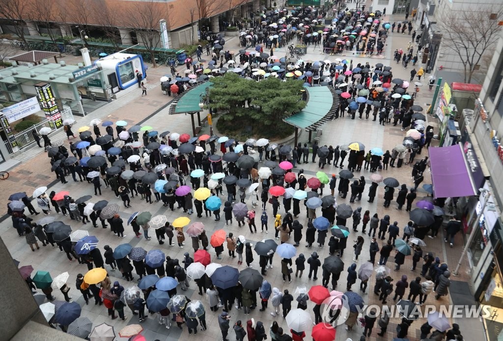 Mọi người tạo thành một hàng dài trong mưa trong một sự kiện bán mặt nạ không lợi nhuận tại một cửa hàng bách hóa ở Seoul vào ngày 28 tháng 2 năm 2020. Giá mặt nạ trong nước đã tăng vọt trong bối cảnh thiếu sản phẩm.(Yonhap)