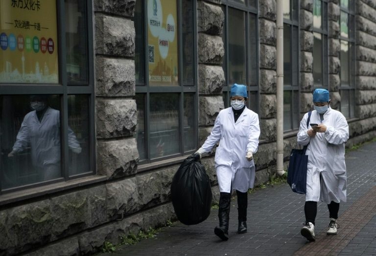 2 nhân viên y tế đi bộ trên 1 con đường vắng vẻ ở Thượng Hải. Ảnh: AFP