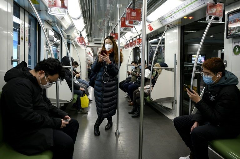 Hành khách trên chuyến tàu điện ngầm vắng vẻ, tất cả đều đeo khẩu trang. Ảnh: AFP