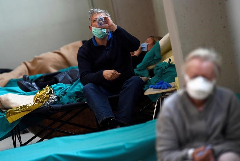Bệnh nhân đeo khẩu trang bảo vệ ngồi bên trong bệnh viện Spedali civili ở Brescia, ngày 13 tháng 3. REUTERS / Flavio Lo Scalzo