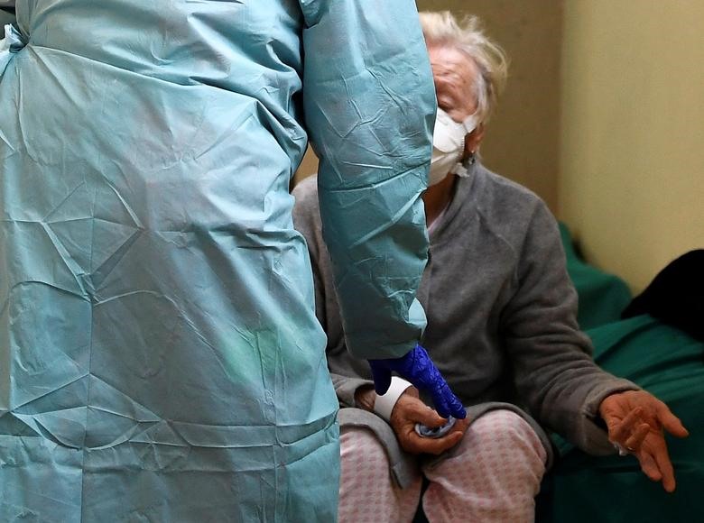 Một bệnh nhân được nhân viên y tế giúp đỡ trong bệnh viện Spedali civili ở Brescia, ngày 13 tháng 3. REUTERS / Flavio Lo Scalzo