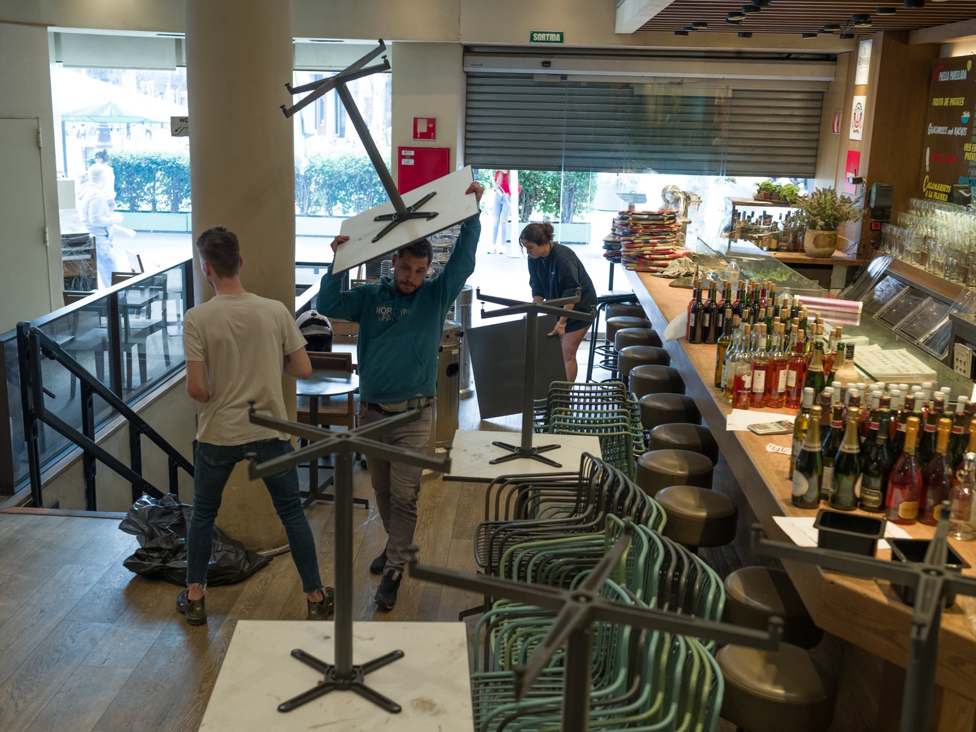 Nhân viên nhà hàng ở Barcelona (Tây Ban Nha) dọn dẹp bàn ghế, hàng quán sau lệnh tạm ngưng hoạt động của chính phủ. Ảnh: The New York Times.