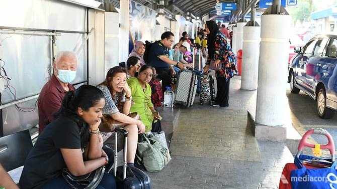 Người dân ngồi đợi xe tại bến xe bus Larkin Sentral, thành phố Johor Bahru (Malaysia)   hôm 17.3 để di chuyển tới Singapore trước khi lệnh phong tỏa có hiệu lực. Johor Bahru được coi là cầu nối giữa Malaysia và Singapore. Ảnh: Vincent Tan.