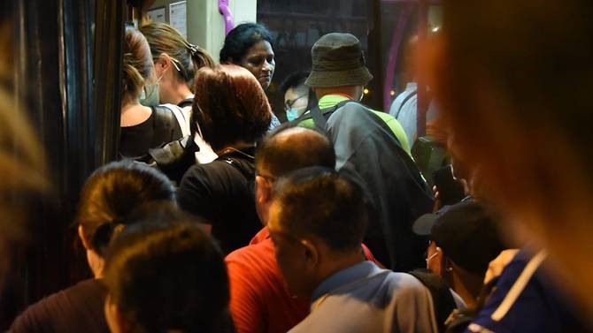 Các hành khách chen chúc nhau lên xe bus ở bên ngoài trạm kiểm soát Woodlands, Singapore đêm 18.3. Ảnh: Try Sutrisno Foo.