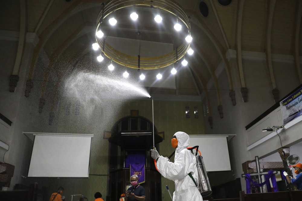 Trong bộ đồ bảo hộ, nhân viên của Cơ quan Giảm nhẹ thiên tai phun thuốc khử trùng tại một nhà thờ ở Surabaya (Java, Indonesia) vào ngày 18.3. Ảnh: AP.
