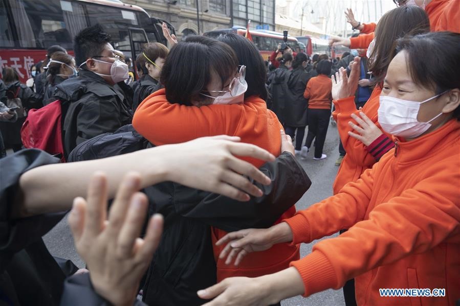 Các y bác sĩ tỉnh Giang Tây (áo màu cam) ôm tạm biệt các đồng nghiệp từ tỉnh Thanh Hải. Họ đã làm việc cùng nhau trong thời gian qua tại 1 bệnh viện thuộc Vũ Hán, Hồ Bắc, Trung Quốc. Ảnh: Xinhua.