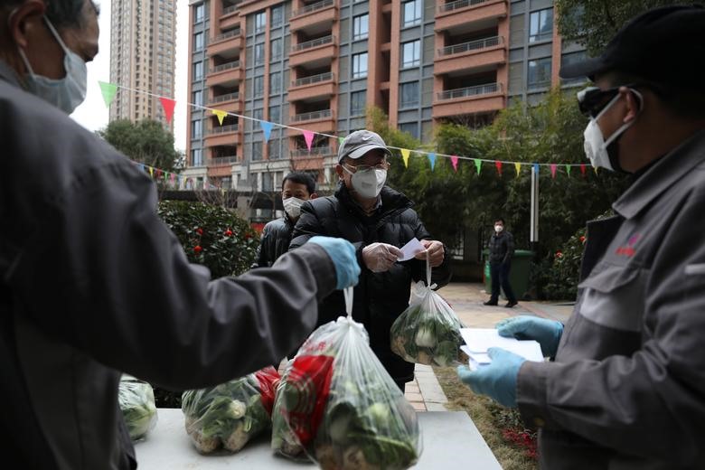 Các nhân viên cộng đồng đang phát rau miễn phí cho các hộ gia đình bên trong một khu dân cư ở thành phố Vũ Hán, tỉnh Hồ Bắc, ngày 11.2. Ảnh: Reuters