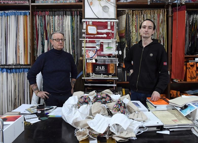 Hai cha con chủ một cửa hàng nhỏ bên những khẩu trang tự làm để phát miễn phí cho mọi người ở thành phố Grosseto, Tuscan, Italia, 17.3. Ảnh: Reuters
