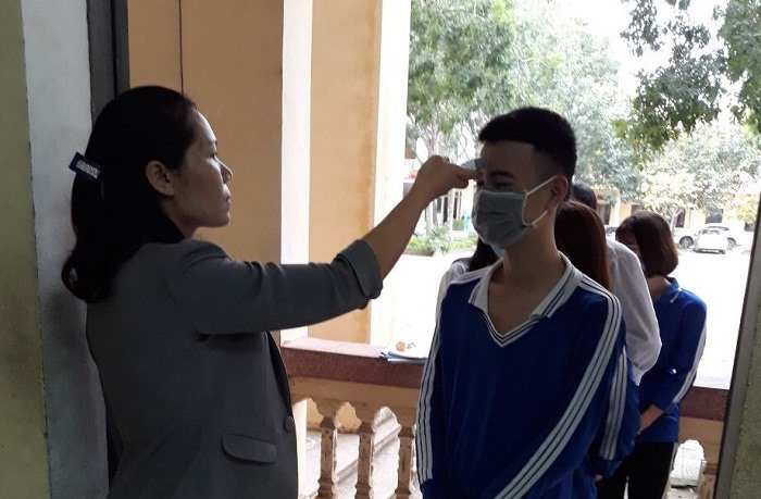 Cô giáo kiểm tra thân nhiệt học sinh khi vào lớp. Ảnh chụp tại Trường THPT Quảng Xương 4. Ảnh: Phong Sắc