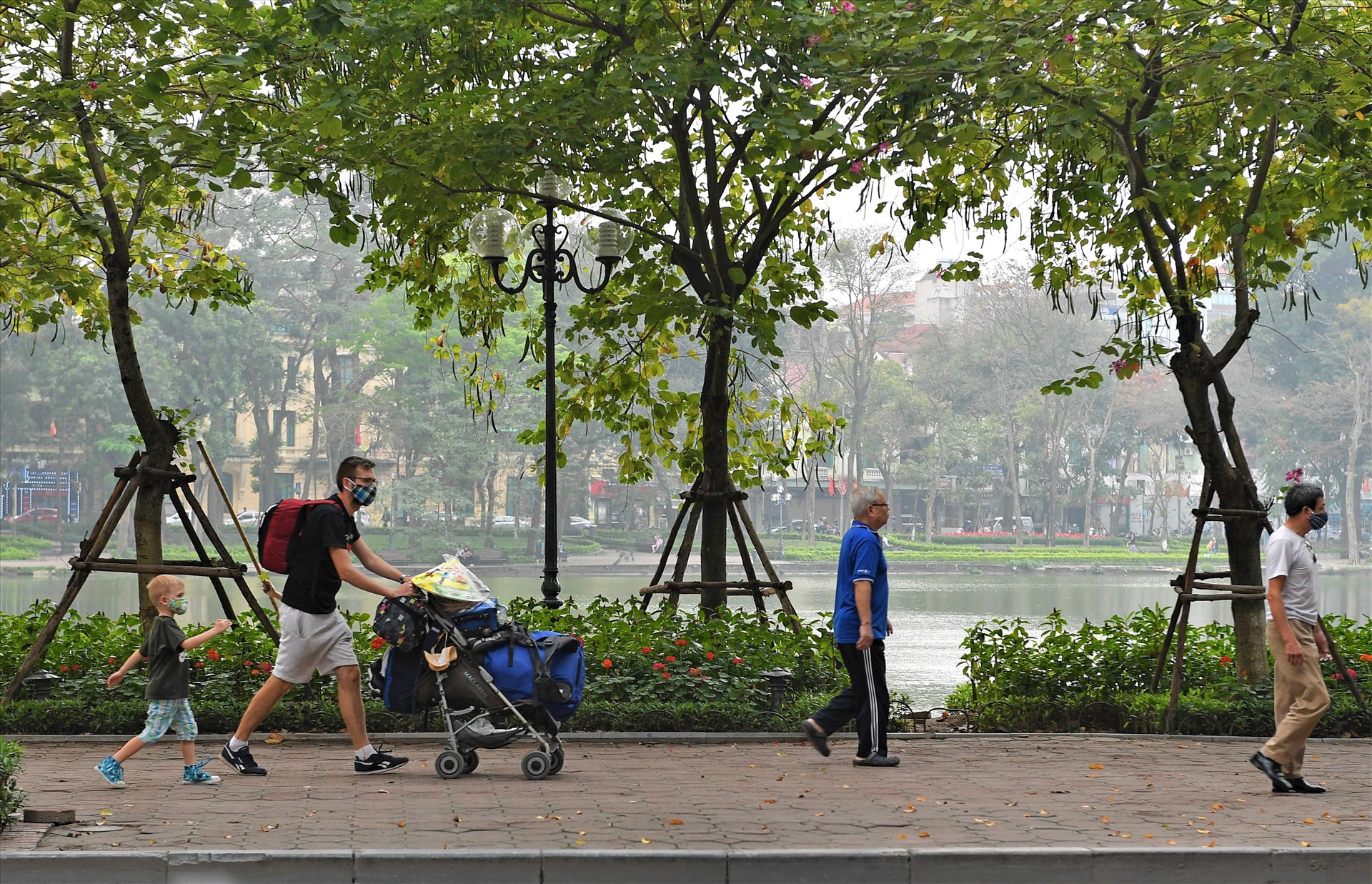 Hai bố con du khách ngoại quốc đeo khẩu trang kín mít đi dạo trên phố.