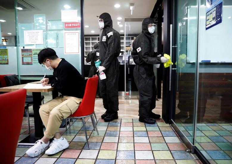 Quân đội Hàn Quốc lau cửa bằng chất khử trùng tại một trung tâm luyện thi để thi tuyển công chức ở Daegu, Hàn Quốc hôm 15.3. Ảnh: Reuters/Kim Kyung-Hoon.