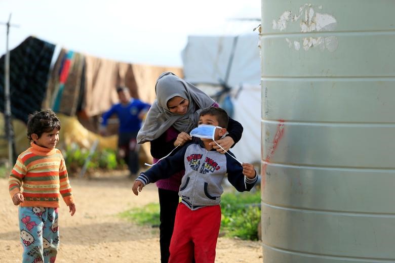 Một phụ nữ tị nạn tại Syria đeo khẩu trang cho cho con để phòng sự lây lan của dịch COVID-19, ở khu vực al-Wazzani, miền Nam Lebanon hôm 14.3. Ảnh: Reuters/Ali Hashisho.