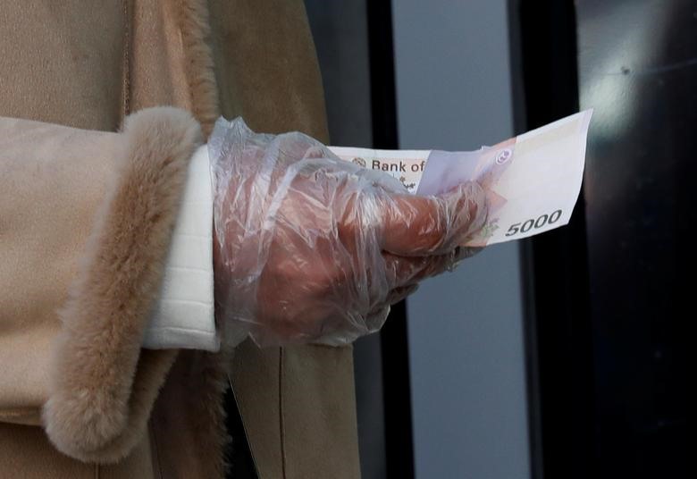 Một người phụ nữ đeo găng tay nilon thanh toán tiền mua khẩu trang tại Daegu, Hàn Quốc. Ảnh: Reuters.