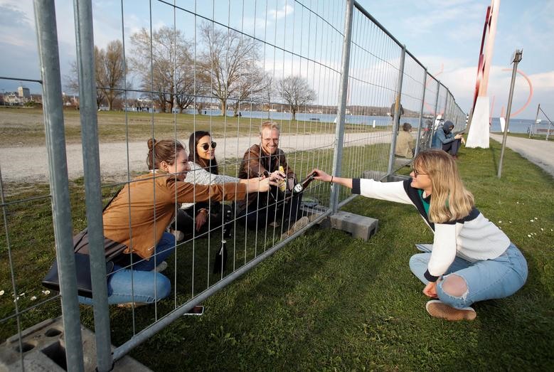 Nhóm bạn gặp gỡ qua hàng rào do chính phủ Đức dựng ở biên giới Đức - Thụy Sĩ tại 1 công viên bên bờ hồ Constance ở Kreuzlingen, Thụy Sĩ hôm 20.3. Ảnh: Reuters/Arnd Wiegmann.
