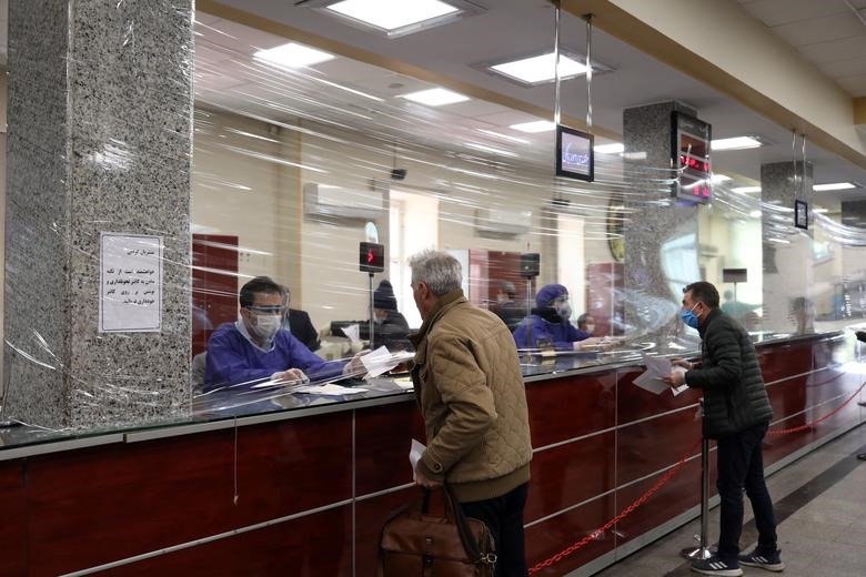 Một tấm chắn bằng nhựa dẻo được dựng nên giữa các nhân viên ngân hàng và khách giao dịch tại Tehran, Iran hôm 17.3. Ảnh: Reuters.