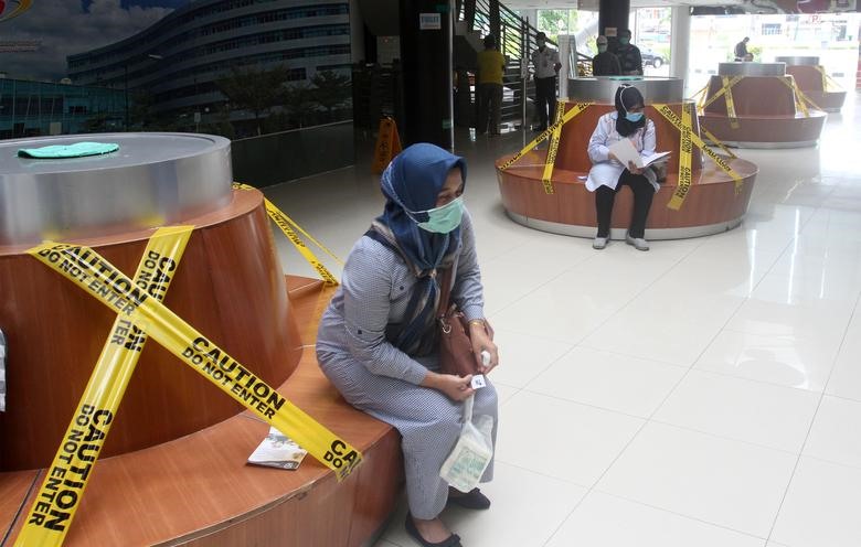 Người dân ngồi cách xa nhau trên băng ghế đợi tại một bệnh viện ở Padang, Tây Sumatera, Indonesia. Ảnh: Antara Foto/Muhammad Arif Pribadi qua REUTERS.
