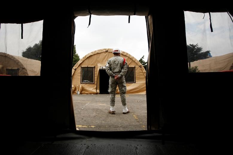 Một binh sĩ đứng gần những chiếc lều được dựng trên bãi đỗ xe của bệnh viện quân sự ở Bogota, Colombia hôm 23.3. Ảnh: REUTERS/Leonardo Munoz.
