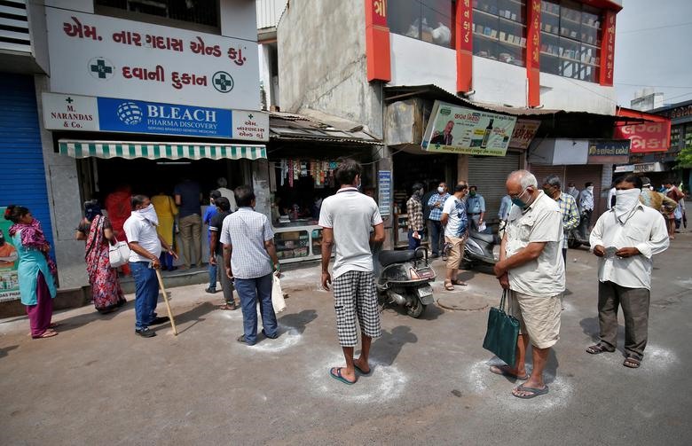 Mọi người đứng thành vòng tròn được vẽ bằng phấn để duy trì khoảng cách an toàn khi họ chờ đợi để mua thuốc ở Ahmedabad, Ấn Độ. Ảnh: Reuter