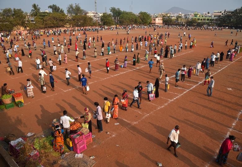 Mọi người duy trì khoảng cách an toàn khi họ xếp hàng để mua rau tại một sân vận động đã biến thành một khu chợ tạm thời trong thời gian khóa trên toàn quốc để hạn chế sự lây lan của coronavirus, ở Vijayawada ở bang miền nam Andhra Pradesh, Ấn Độ,