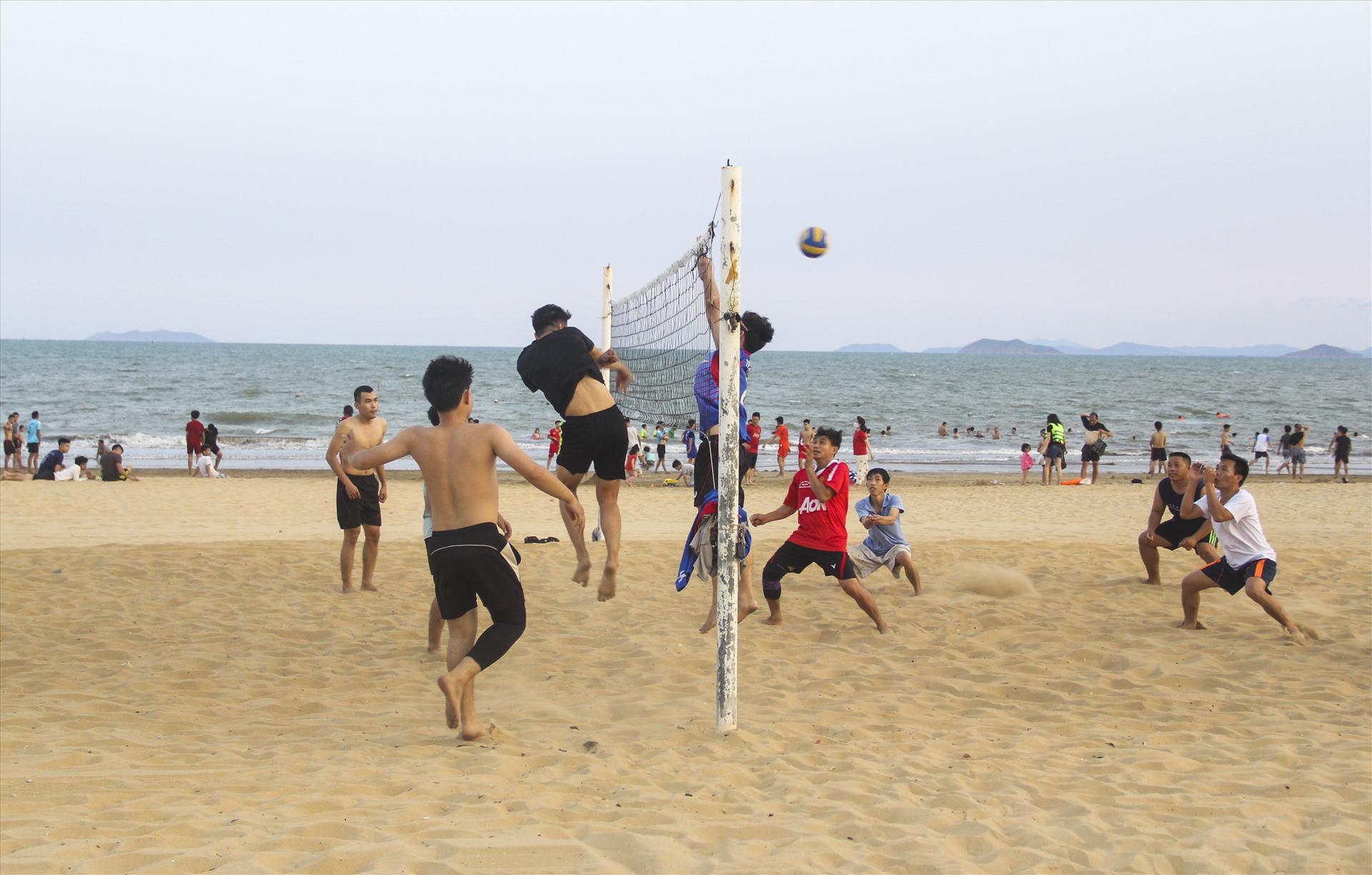 Bãi biển đông đúc người dân tụ tập thành từng nhóm: nhóm thì chơi đùa, nhóm tắm biển, nhóm đánh bóng chuyền....