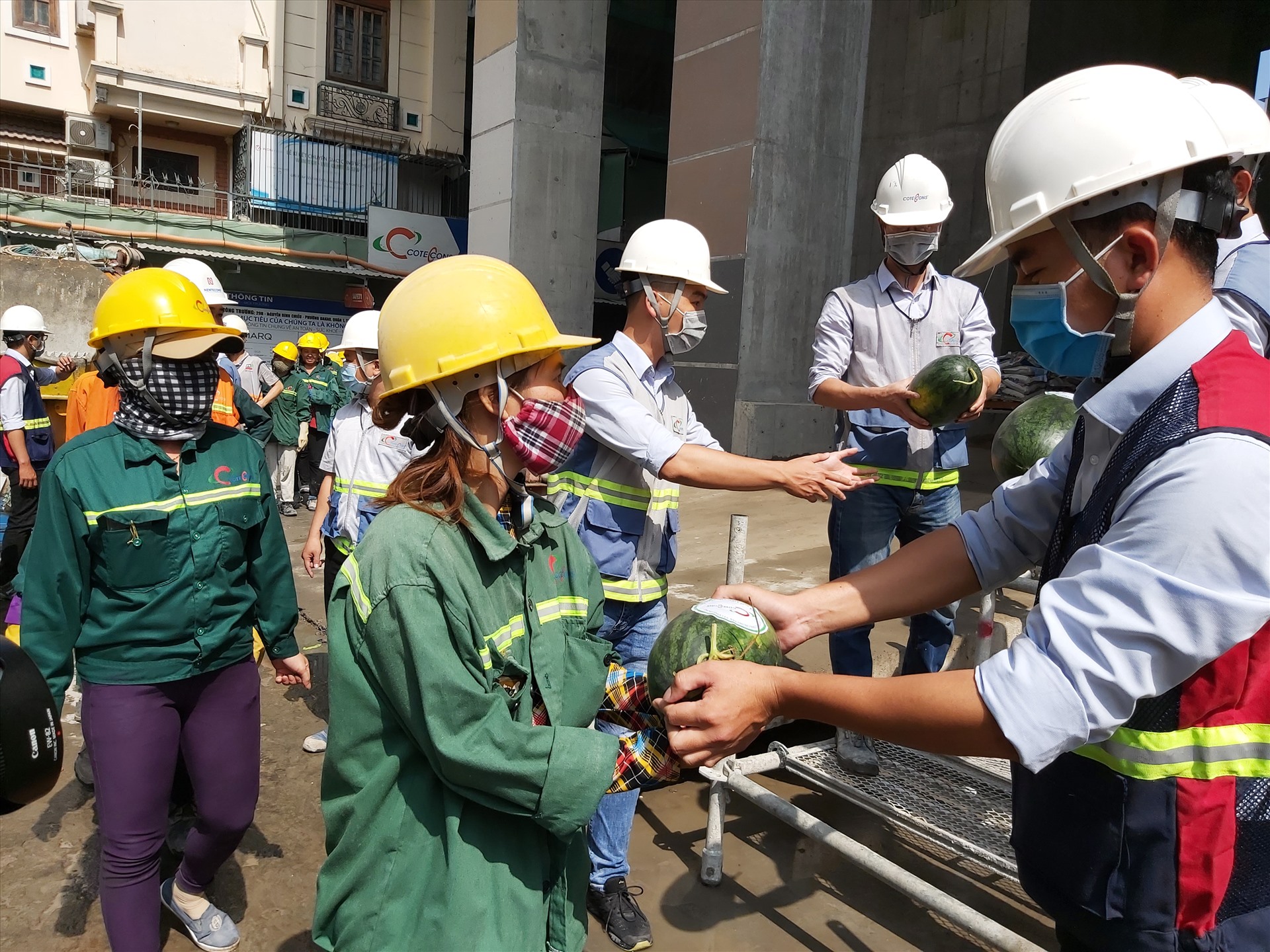 Các công nhân trên công trường xây dựng nhận dưa hấu do Công đoàn Công ty Coteccons phát miễn phí. Ảnh Nam Dương