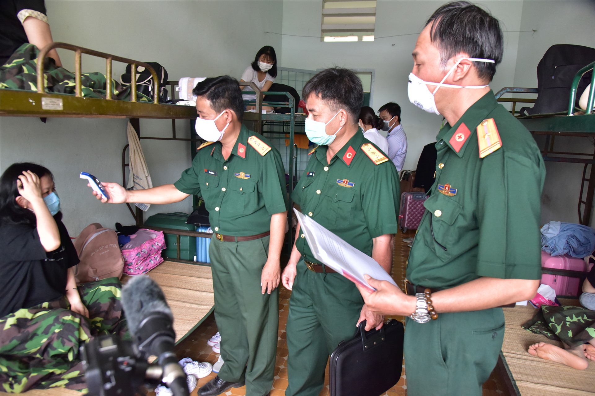 Cán bộ Trường quân sự của Quân khu 9 tại tỉnh Sóc Trăng kiểm tra thân nhiệt cho các hành khách cách ly. Ảnh: Thành Nhân