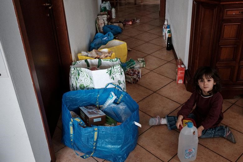 Em bé 2 tuổi Bianca Toniolo ngồi bên đống đồ ăn tích trữ của cả nhà trị giá 300 euro, ở San Fiorano, ngày 25.2. Ảnh: Reuters