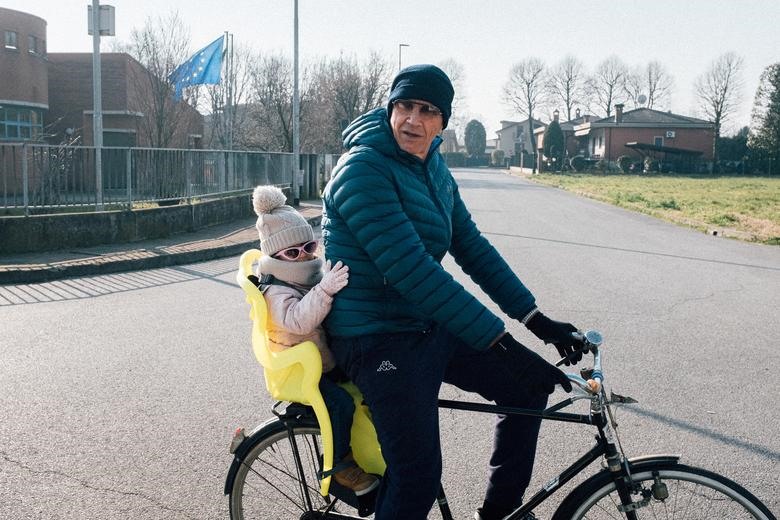 Ông Massimo Toniolo, 61 tuổi, xe đạp chở cháu gái Bianca, 2 tuổi, ở San Fiorano, ngày 22.2. Ảnh: Reuters
