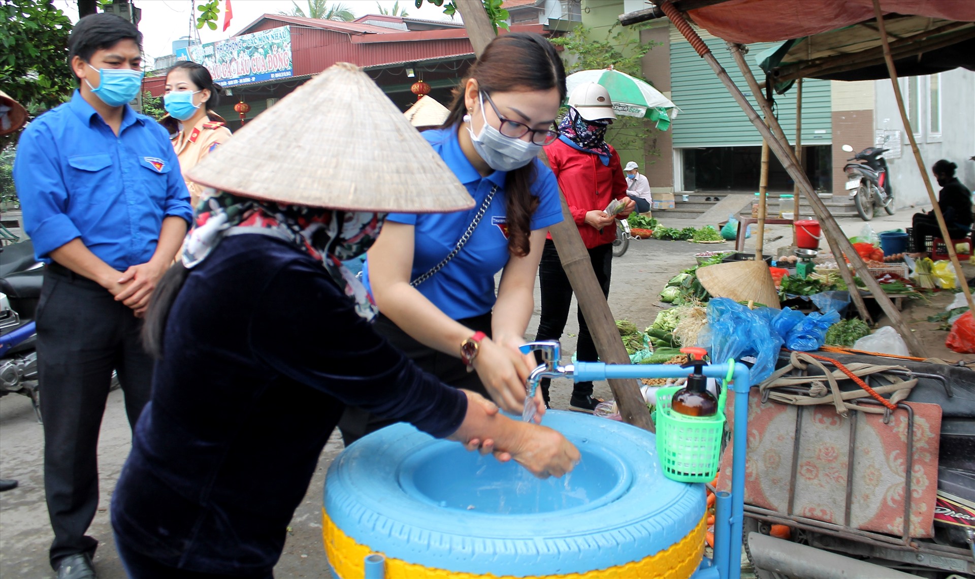 Đoàn viên, thanh niên hướng dẫn tiểu thương chợ Lương Quán rửa tay 6 bước theo quy định. Ảnh Mai Dung