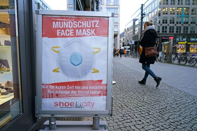 Tấm bảng khuyên khách hàng nên đeo khẩu trang được đặt bên ngoài một cửa hàng bán giày ở Berlin (Đức). Ảnh: AFP.