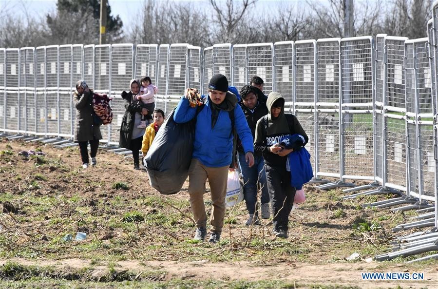 Một nhóm các thành viên gia đình người di cư đi dọc theo hàng rào biên giới để tìm cách vượt qua. Ảnh: Tân Hoa Xã