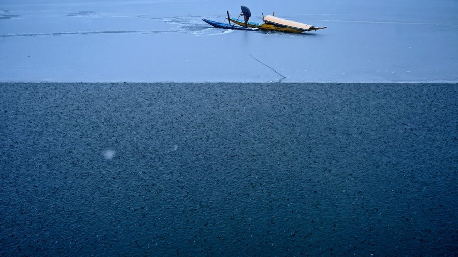 Srinagar, Ấn Độ: Người đàn ông đang gắng sức dẫn chiếc thuyền của mình ra khỏi lớp băng dọc theo hồ Dal, được gọi là “Hồ hoa“, khi tuyết rơi ở thủ đô mùa hè của Kashmir do Ấn Độ kiểm soát. Ảnh: Tauseef Mustafa