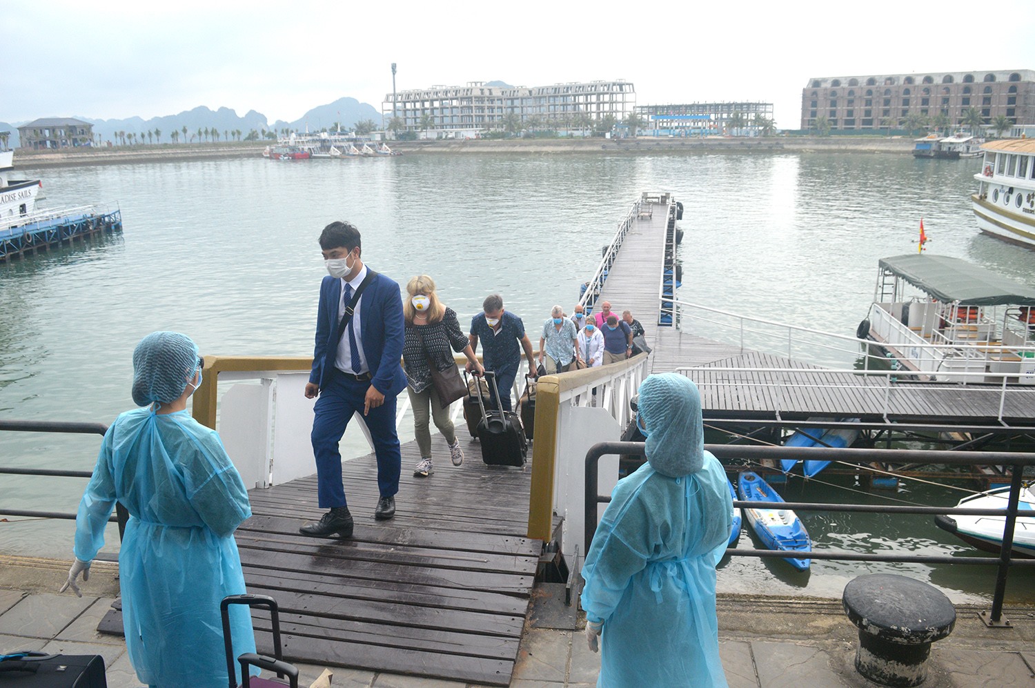 Hành khách trên tàu nghỉ đêm cập cảng Tuần Châu được nhân viên y tế Quảng Ninh hưỡng dẫn đưa đi cách ly. Ảnh: BQN