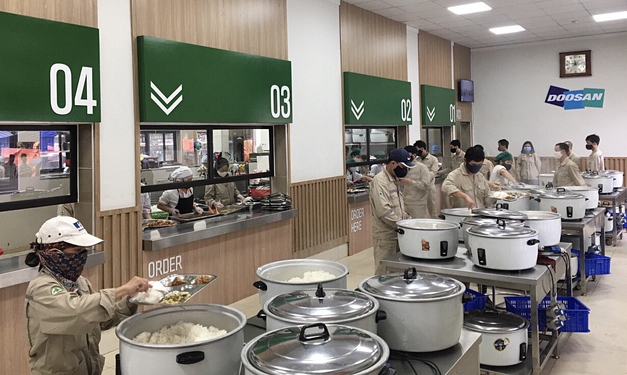 Người lao động giữ khoảng cách khi lấy đồ ăn tại bếp ăn tập thể Công ty Doosan Vina. Ảnh ĐL