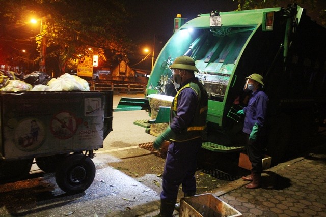 Anh Tùng (bên phải) cùng đồng nghiệp phụ trách đưa rác từ xe thu gom lên xe lớn. Ảnh: Trần Tuấn