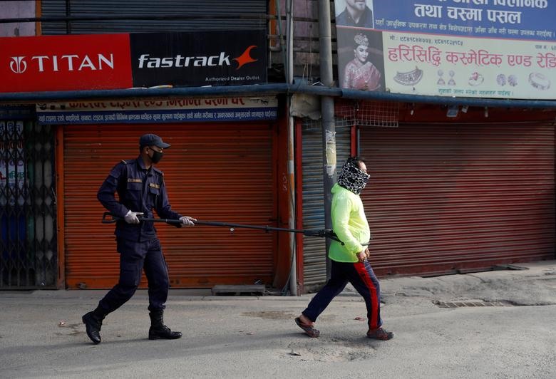 Cảnh sát Nepal duy trì khoảng cách bằng chiếc gậy khi bắt giữ một người không chấp hành lệnh giãn cách xã hội của Chính phủ. Hình ảnh ghi nhận ởtại Thủ đô Kathmandu. Ảnh: Reuters.