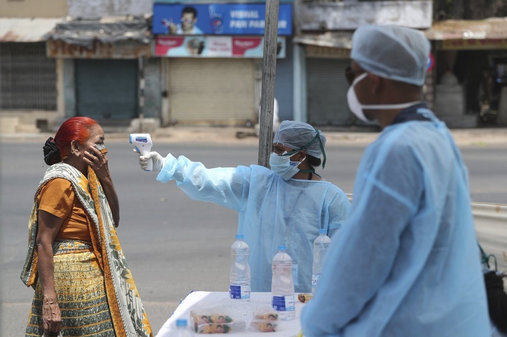 Nhân viên y tế kiểm tra nhiệt độ của một người phụ nữ ở Ahmedabad (Ấn Độ) trong thời gian đất nước áp dụng lệnh phong tỏa. Ảnh: AP.