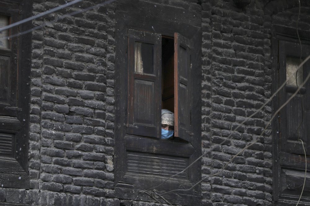 Một phụ nữ Kashmir (Ấn Độ) nhìn ra không gian bên ngoài từ cửa sổ của ngôi nhà. Ảnh: AP.
