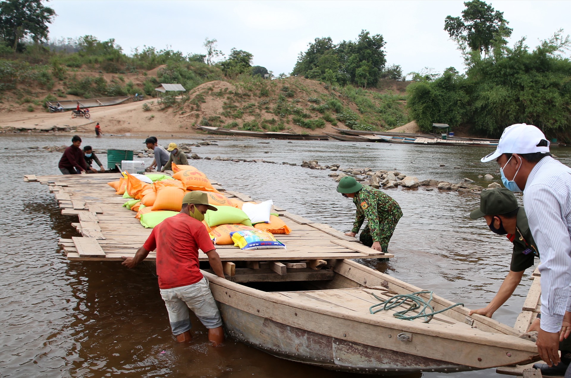 Biên phòng Quảng Trị hỗ trợ đẩy thuyền chở gạo và vật tư y tế qua vùng nước cạn.