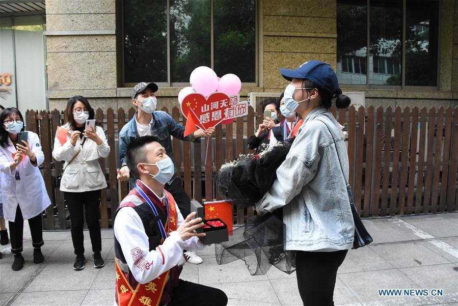 Zhang Jian, nhân viên y tế của đoàn hỗ trợ chống dịch COVID-19 cho Hồ Bắc đang cầu hôn bạn gái tại Hàng Châu, Chiết Giang sau khi trở về hôm 15.4. Có 1.010 nhân viên y tế Chiết Giang đã đoàn tụ với gia đình sau khi hết hạn cách ly. Ảnh: Xinhua.