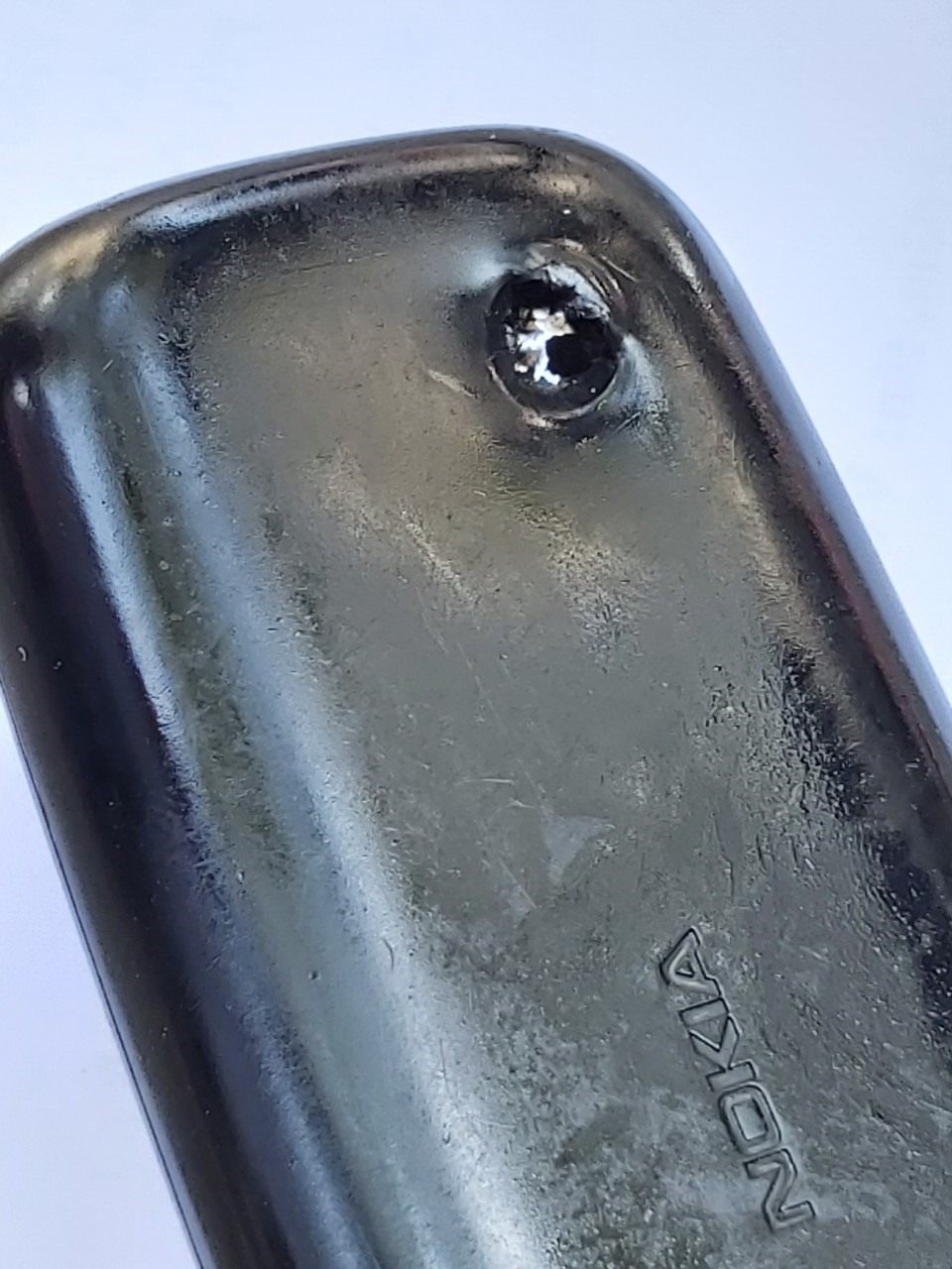 Chiếc điện thoại của anh Tâm có một lỗ thủng ở góc trên giống như vết đạn bắn xuyên qua. Ảnh Nam Dương.